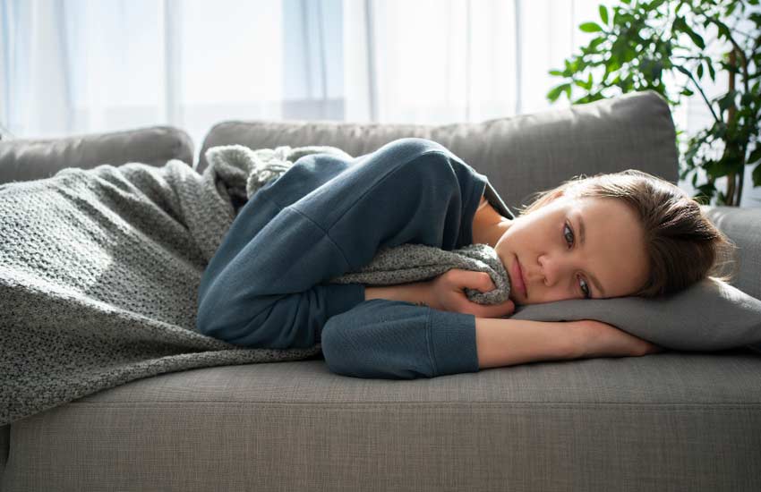 zabrinuta i bolesna djevojka leži na kauču